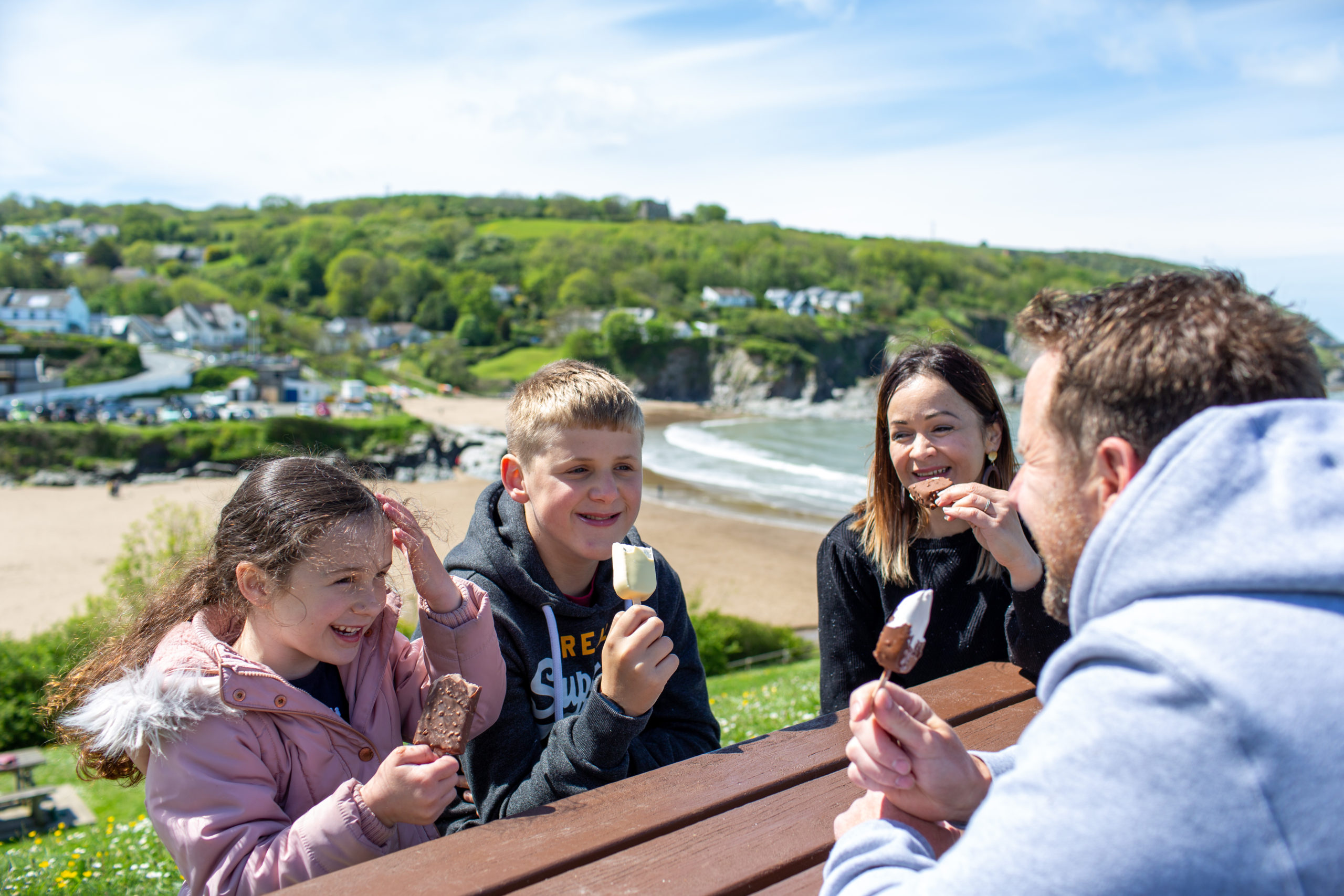Two adults and two children eating ice-cream overlooking bay